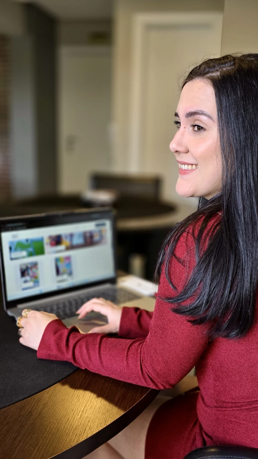 Vitória Pithan sorrindo enquanto trabalha em um notebook