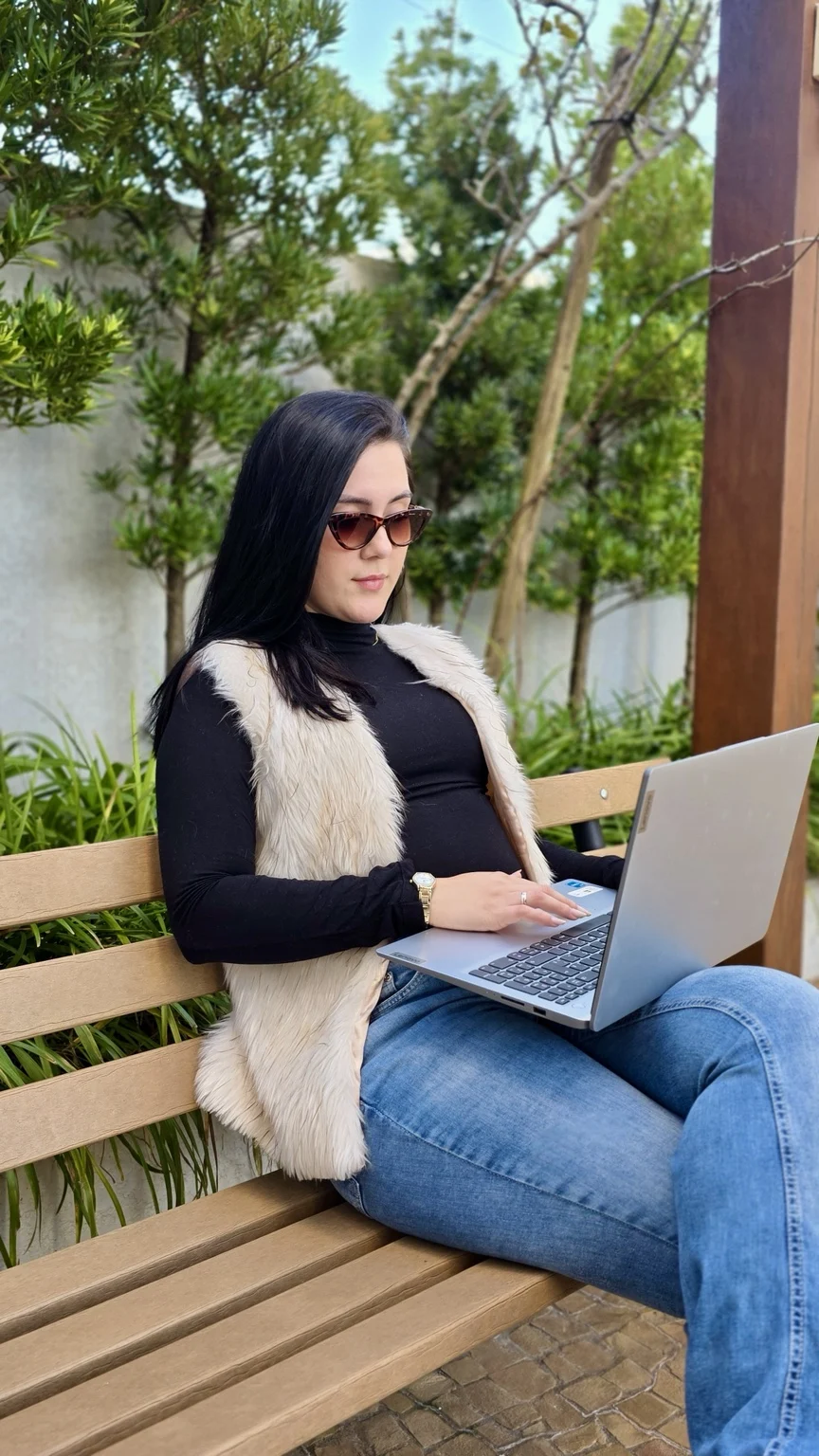 Vitória Pithan trabalhando com notebook ao ar livre